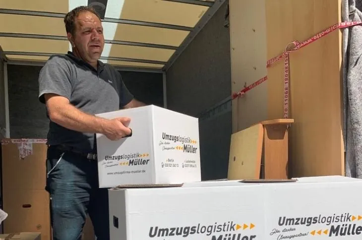 umzugshelfer laedt umzugskartons in umzugswagen