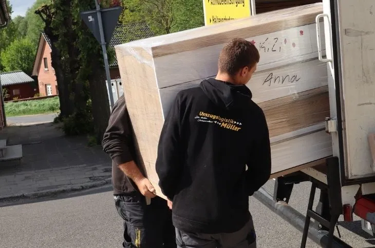 zwei umzugshelfer laden verpackten schrank in umzugswagen